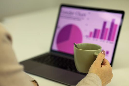 Person reviewing charts on a laptop with a cup of coffee